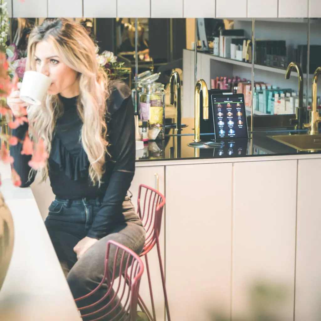 Woman enjoying a TopBrewer coffee next to a TopBrewer with gold swan neck