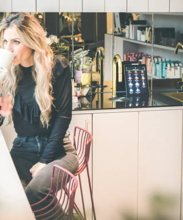Woman enjoying a TopBrewer coffee next to a TopBrewer with gold swan neck