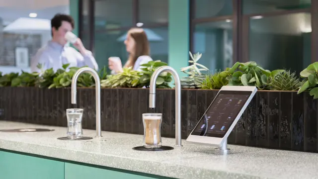 Image showing a TopBrewer commercial coffee machine and TopWater water dispenser with two people chatting in the background