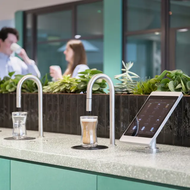 Image showing a TopBrewer commercial coffee machine and TopWater water dispenser with two people chatting in the background