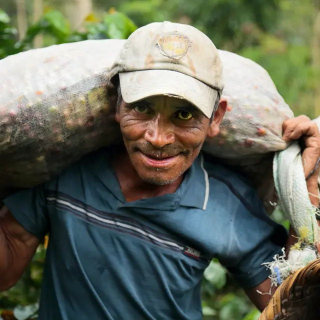 Cafenor coffee farmer with bag of coffee cherries