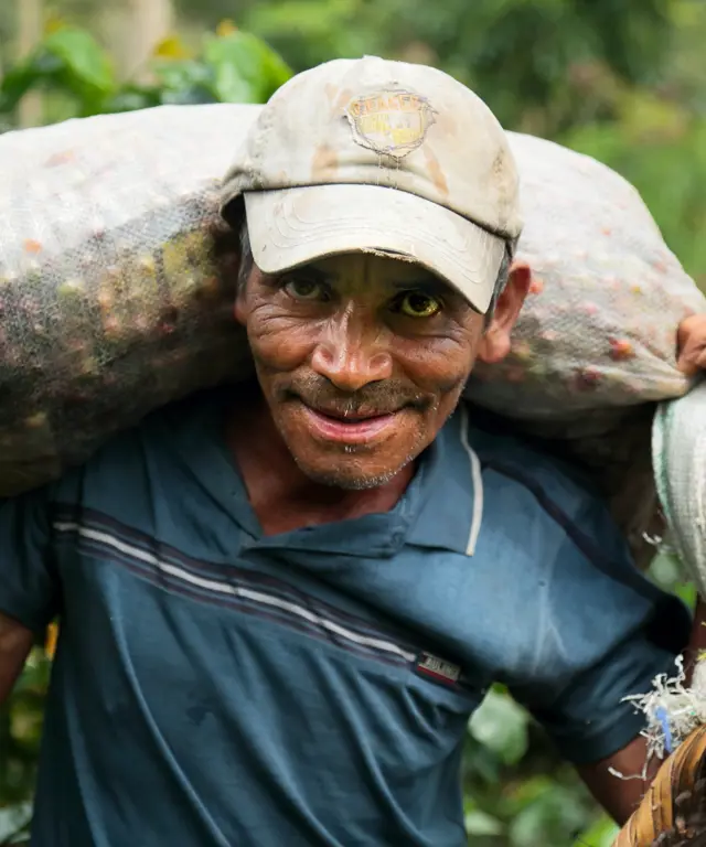 Cafenor coffee farmer with bag of coffee cherries