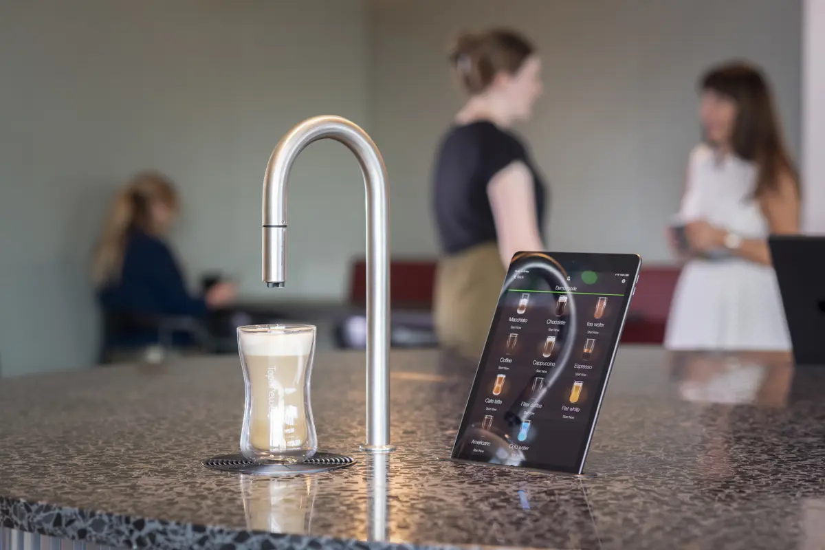 Image showing TopBrewer commercial coffee machine in the foreground with people chatting and working on laptops in the background