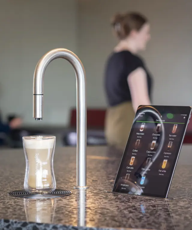 Image showing TopBrewer commercial coffee machine in the foreground with people chatting and working on laptops in the background