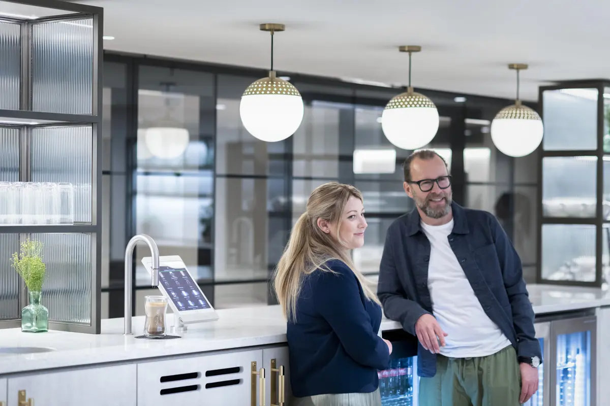 Two people chat next to a TopBrewer coffee machine