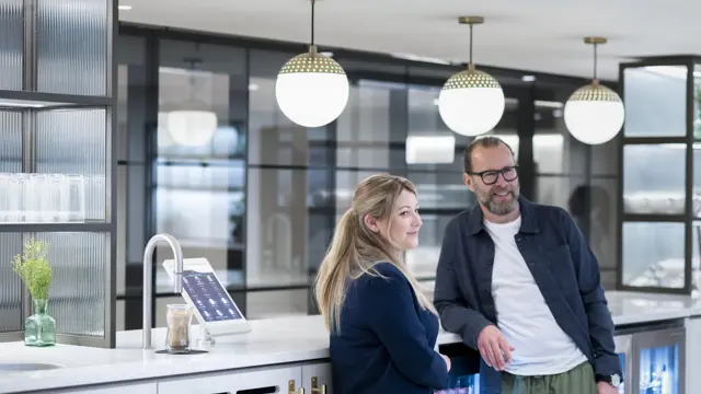 Two people chat next to a TopBrewer coffee machine