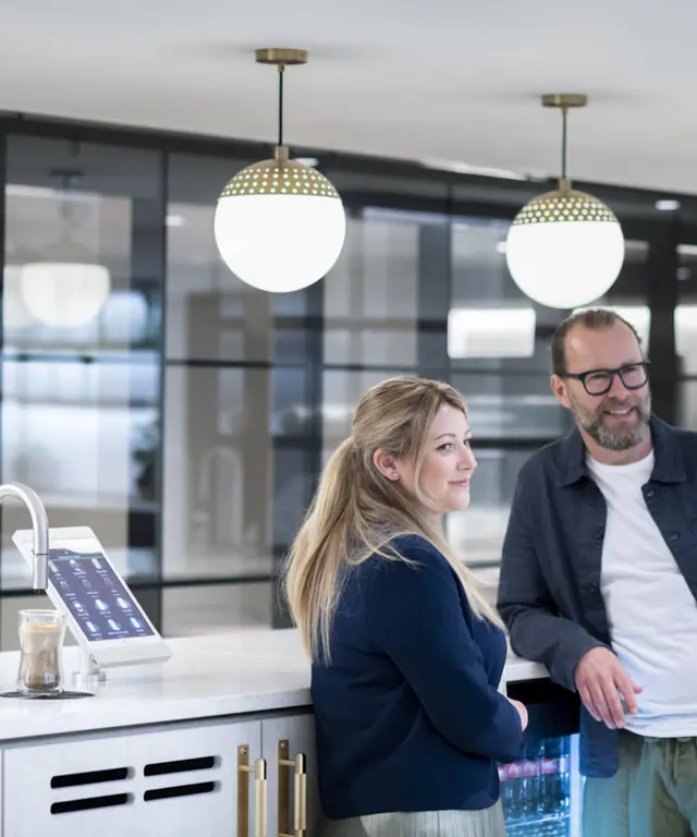 Two people chat next to a TopBrewer coffee machine